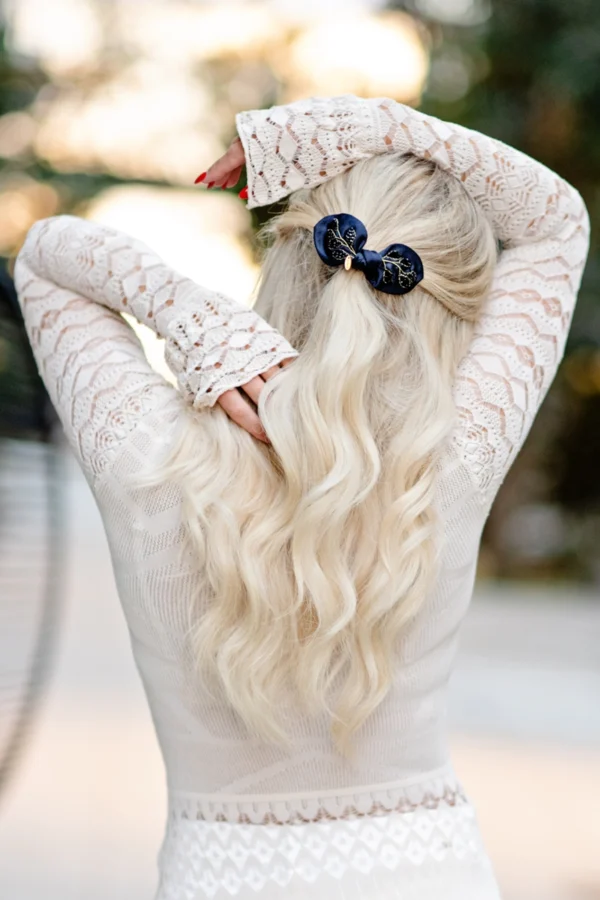 blonde woman hair half up with navy silk satin hair bow with black crystal embellishment