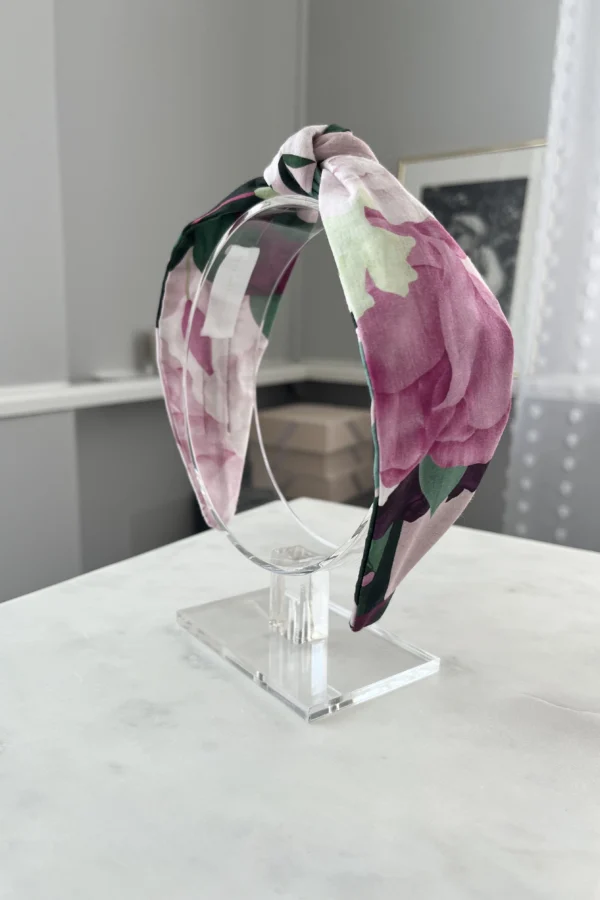 cotton headband with peony print sitting on a headband stand